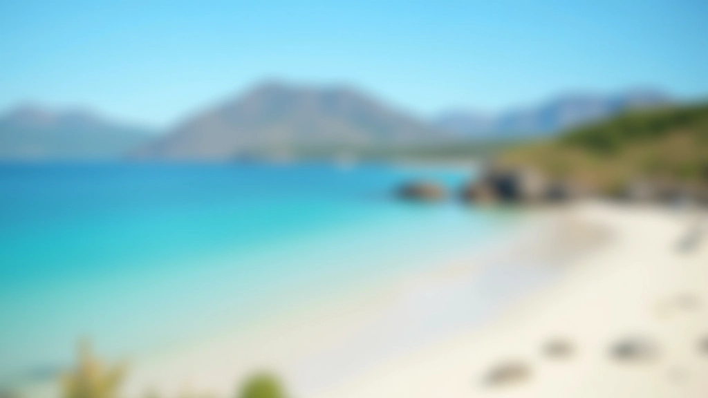 Turquoise water meeting white sandy beach with mountain peaks visible in the distance under clear sky